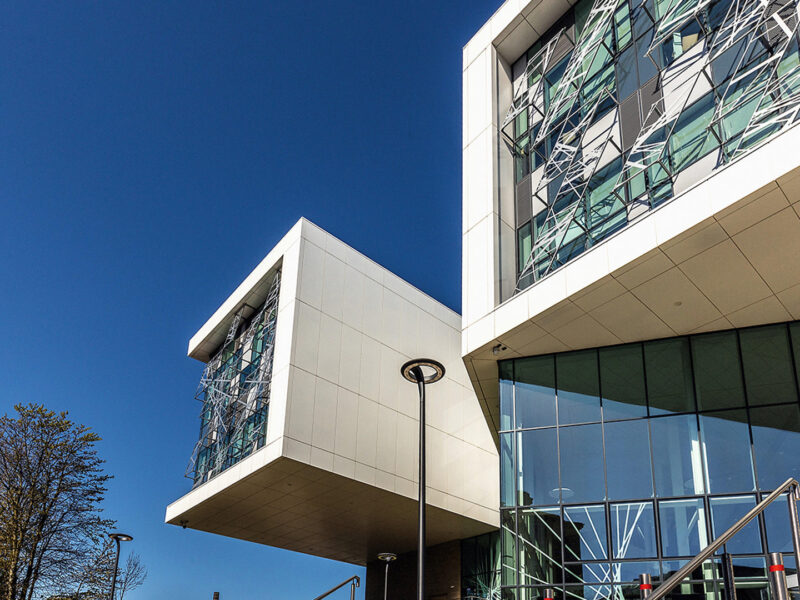 The outside of the University of Huddersfield building featuring large windows and white tiles.
